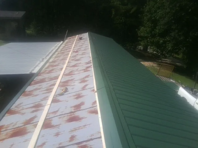 Old rusted panels beside newly installed green metal roofing — Wind Damage Roof Repair by Roofing Brothers in Wheeler